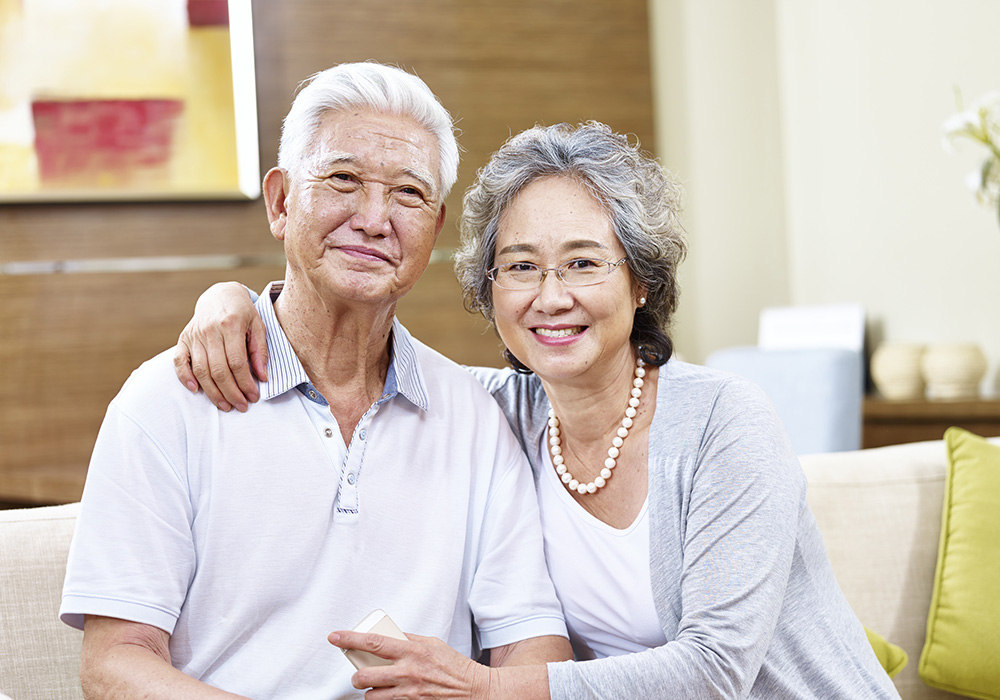 active senior living couple on a sofa smiling at UV thousand oaks