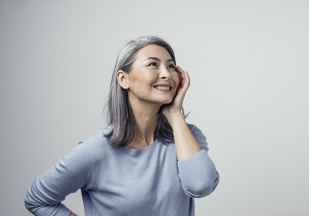 A woman smiling and touching her face