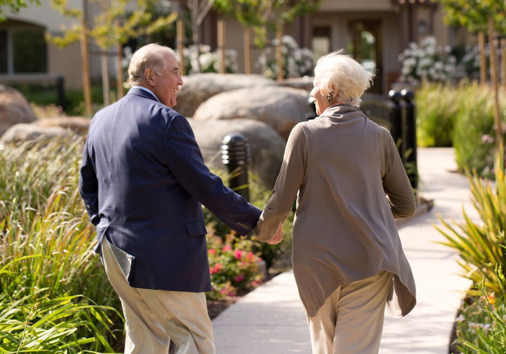 A mature couple walking and holding hands outdoor sidewalk