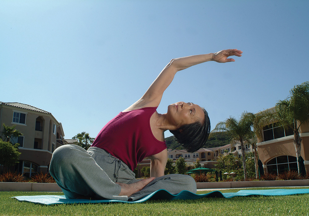 A senior woman doing stretching exercises outside.