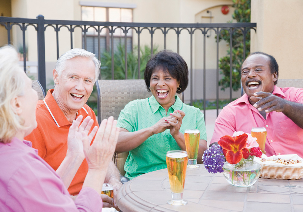 4 mature adults enjoying beer on the outdoor eating area