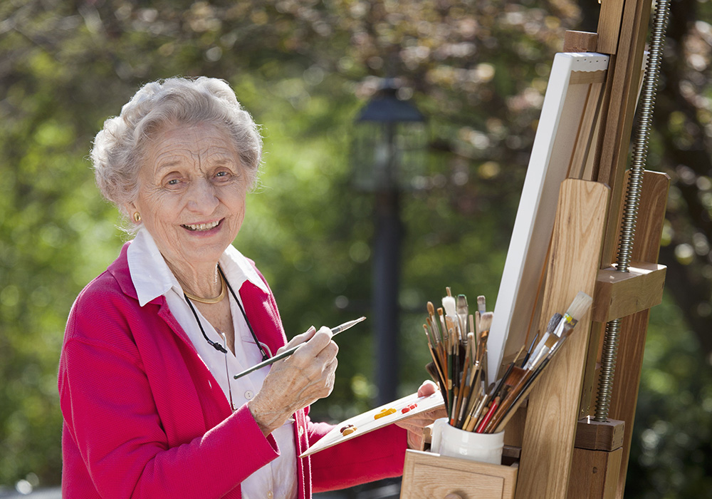 Woman outside painting with canvas on an easel.