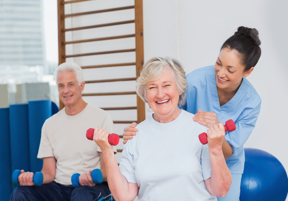 Woman holding red weights in an exercise class with help from instructor.