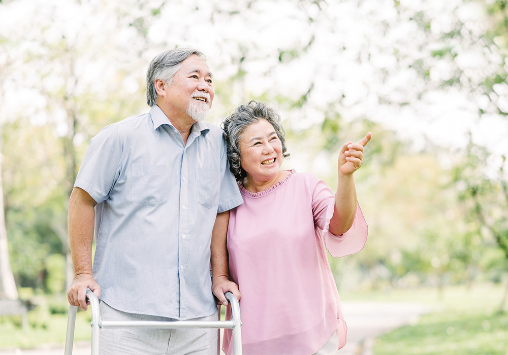 An elderly couple smiling while on a walk in the park