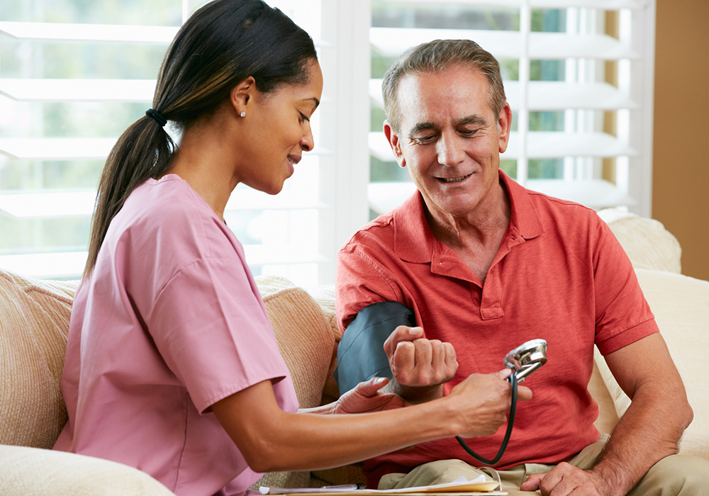 oakview-1000x700-12 African American caregiver taking the blood pressure of an elderly Hispanic man