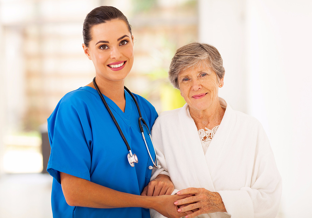 Healthcare worker in blue scrubs with woman in robe
