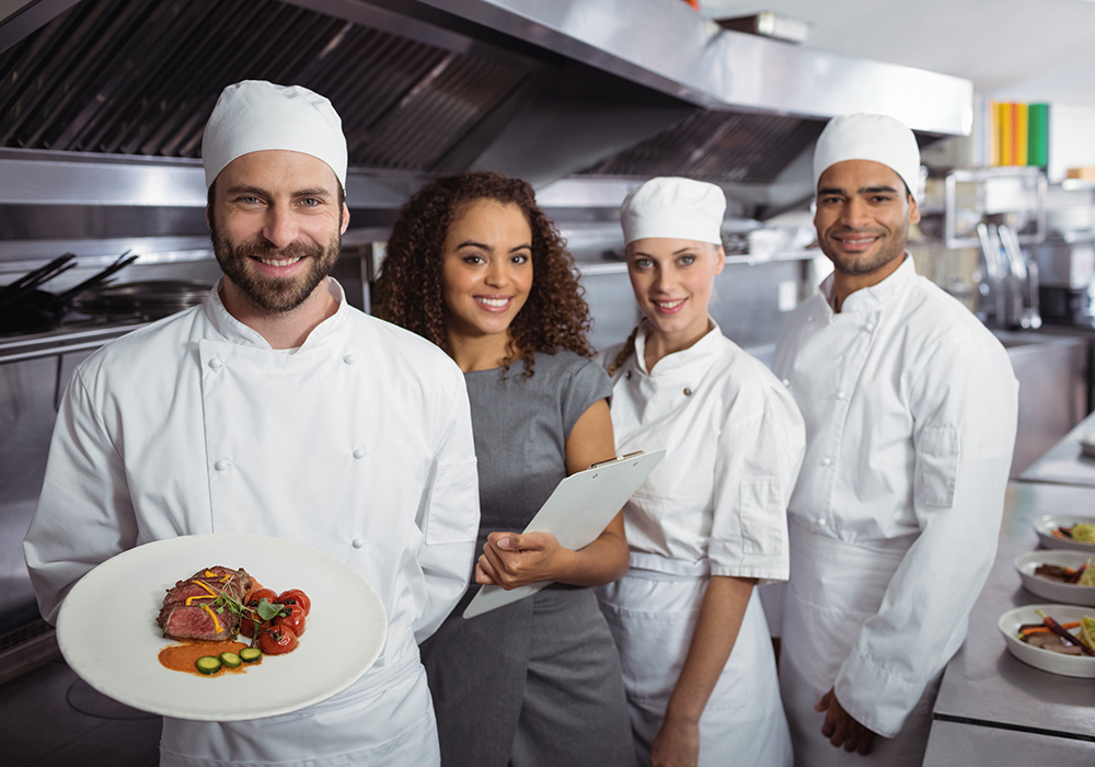 Chefs in an industrial kitchen with plated tri-tip