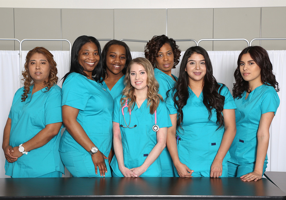 Group of healthcare wrokers in teal colored scrubs in a hospital room