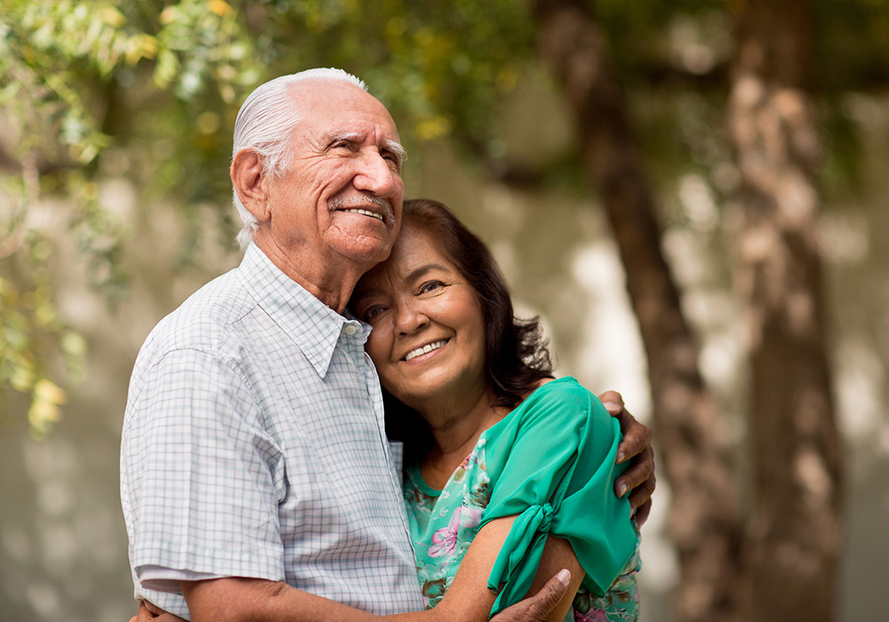 An elderly hispanic couple embracing and smiling