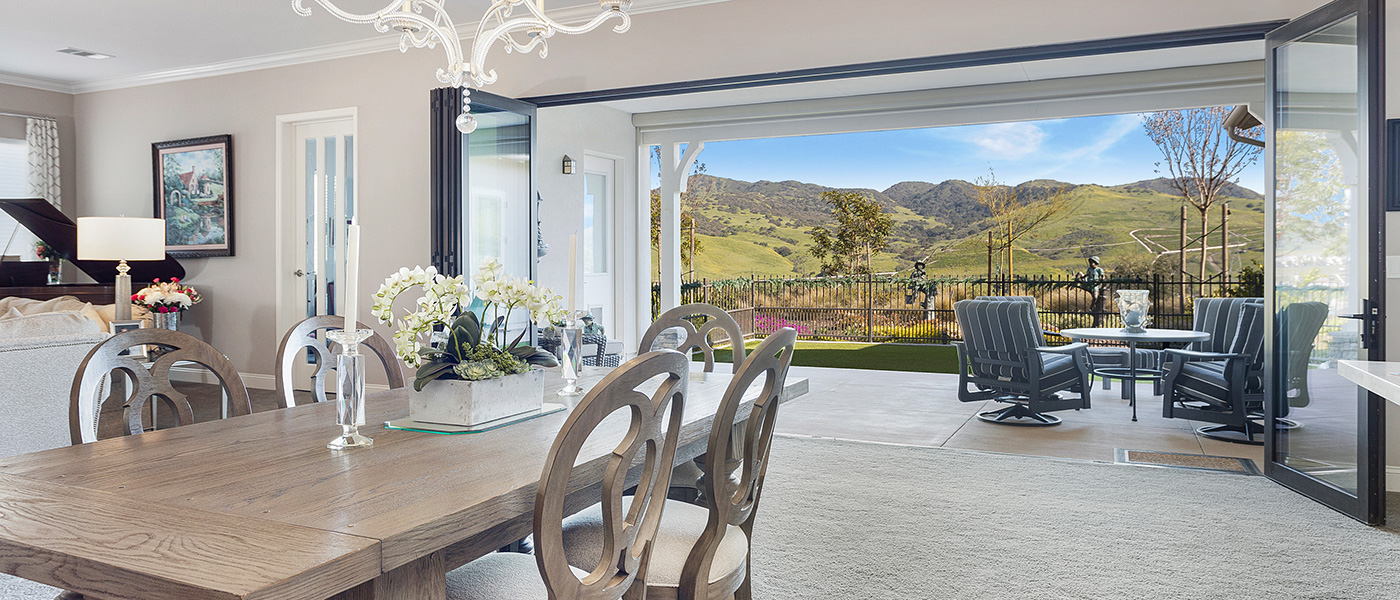 In the living room of a villa looking out through the accordion doors to the green hills