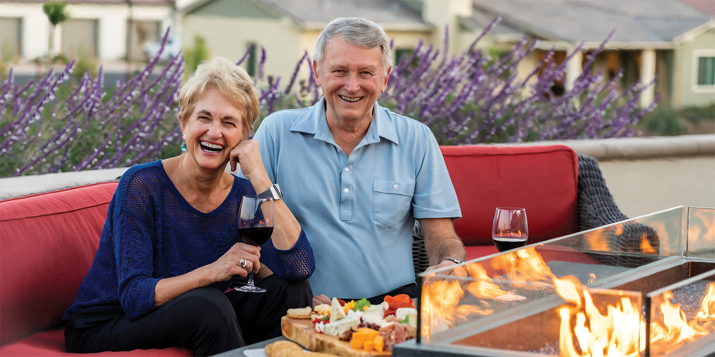 A couple sitting next to an outdoor fire pit with wine and charcuterie