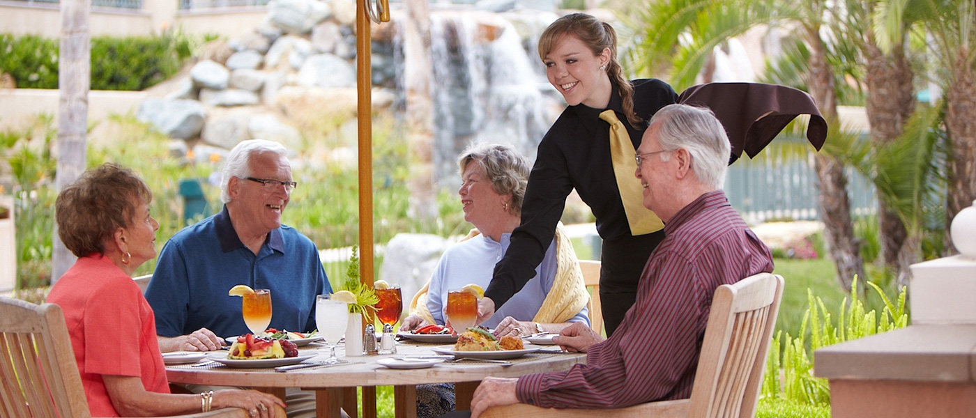 lacosta-2024-1400x600-8 A group of residents eating outdoors at a restaurant at La Costa Glen