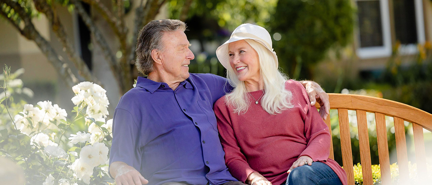 A happy couple sitting on a bench at La Costa Glen