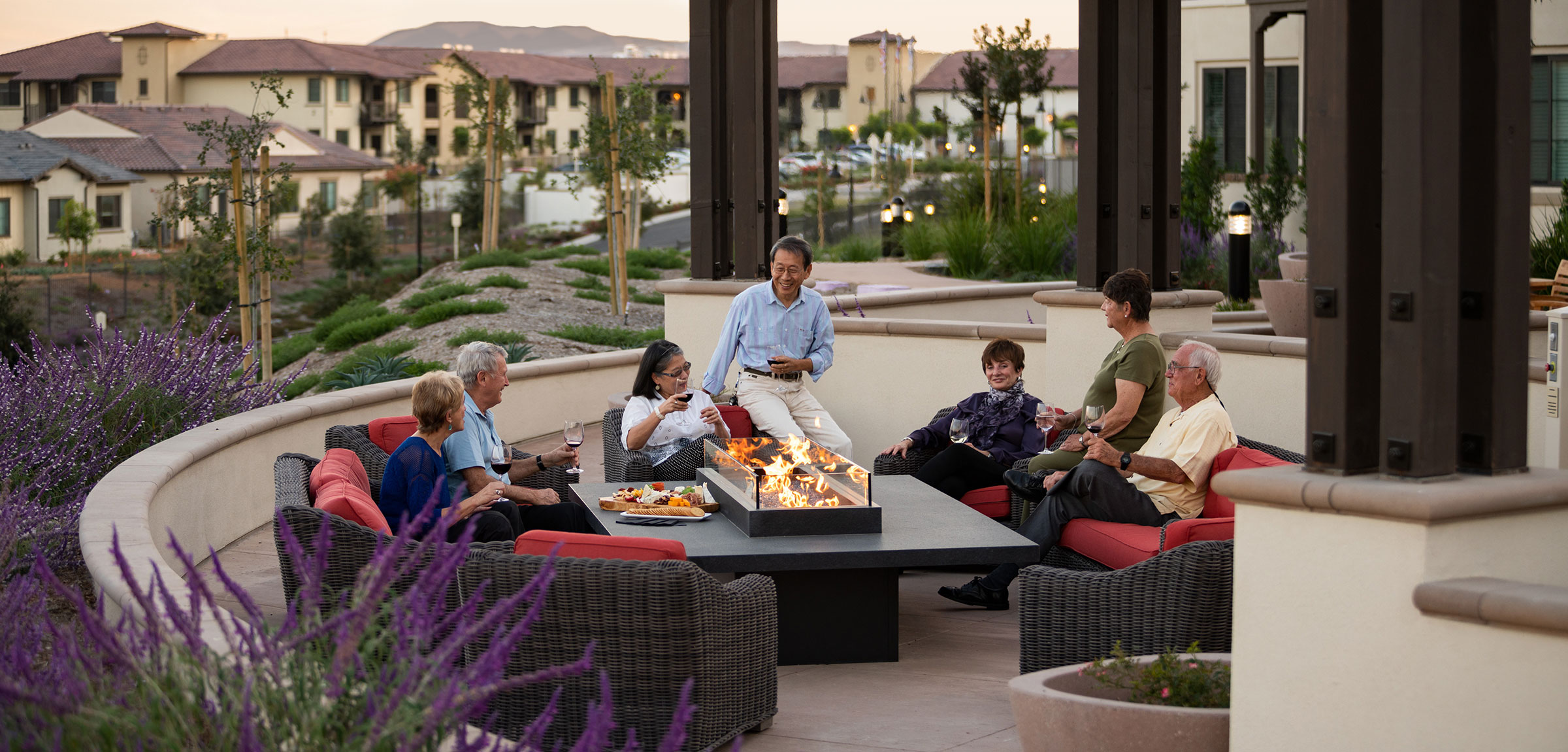 Residents sitting around an outdoor firepit drinking wine.
