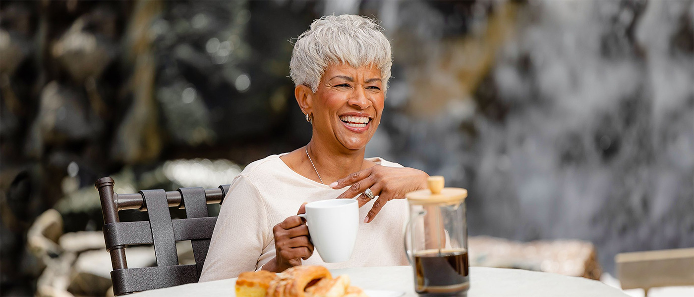 a woman sitting outside drinking coffee and eating pastries