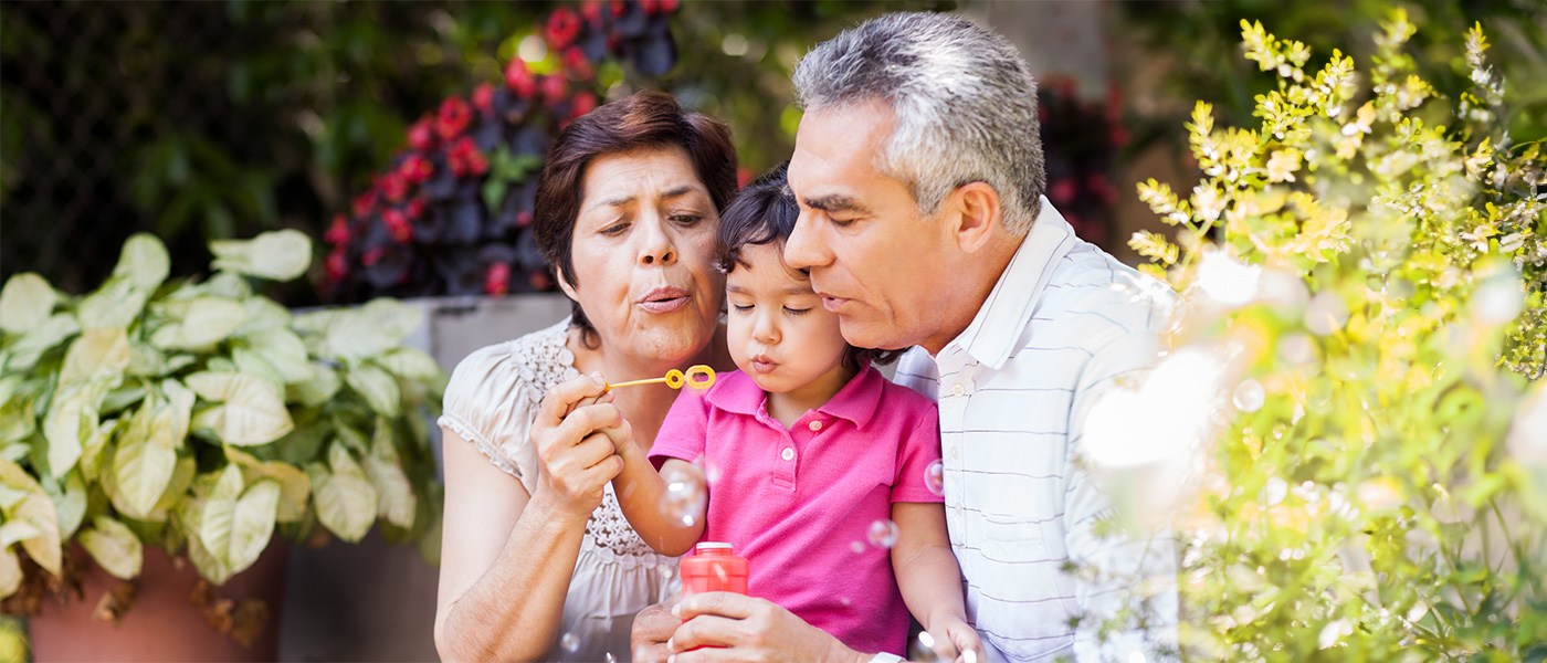 Grandparents sitting with a little girl blowing bubbles