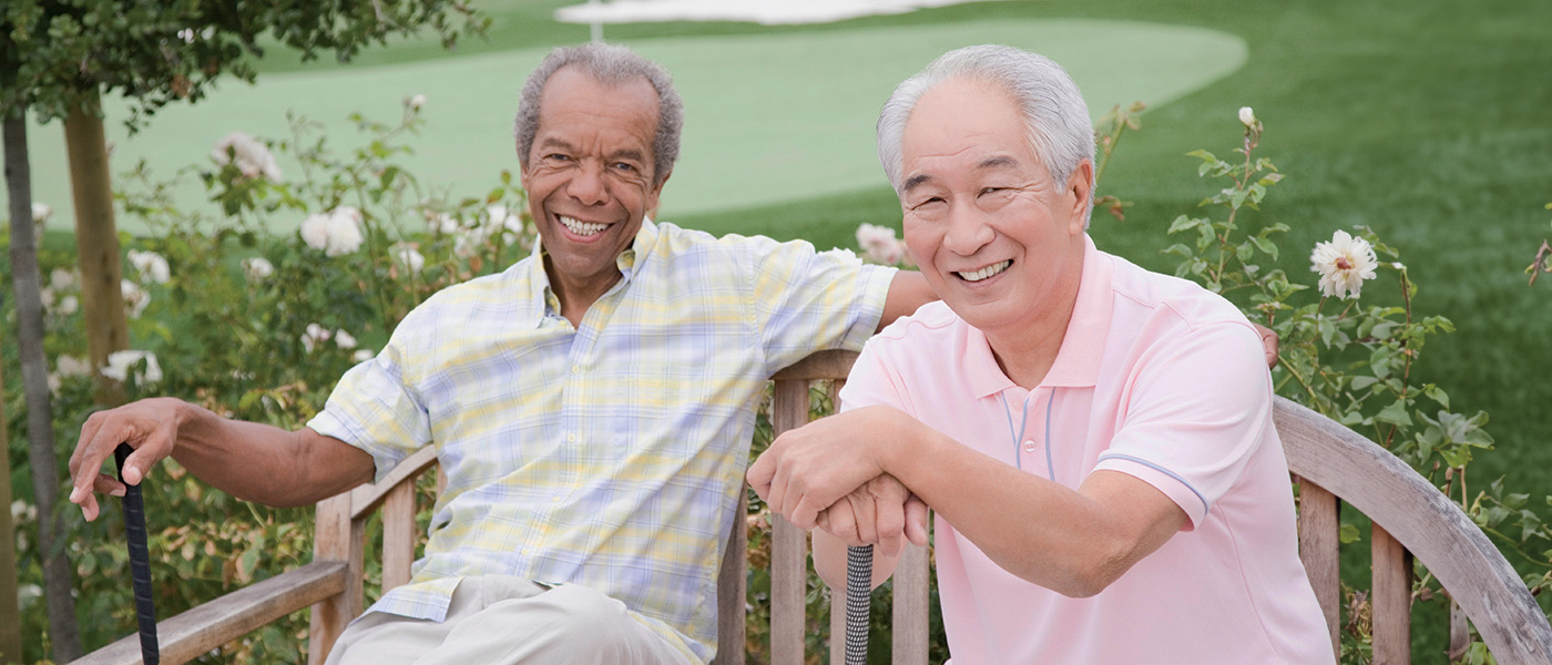 Two men playing golf together taking a break on a bench